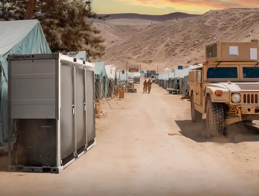 Military camp with tents, portable toilets, two soldiers walking, and a military vehicle on dusty road.