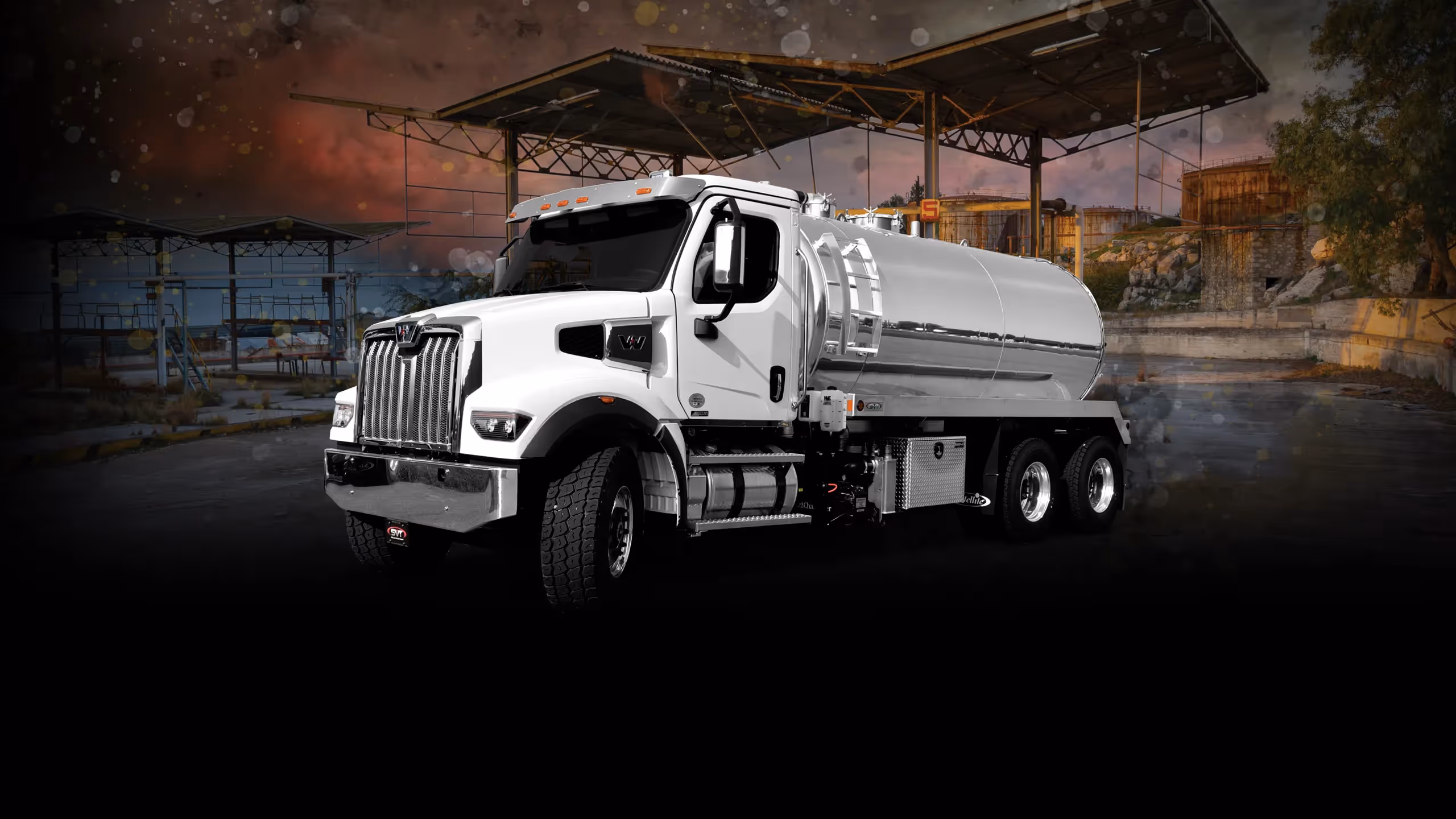 White fuel tanker truck with a large chrome tank, set against an industrial background.