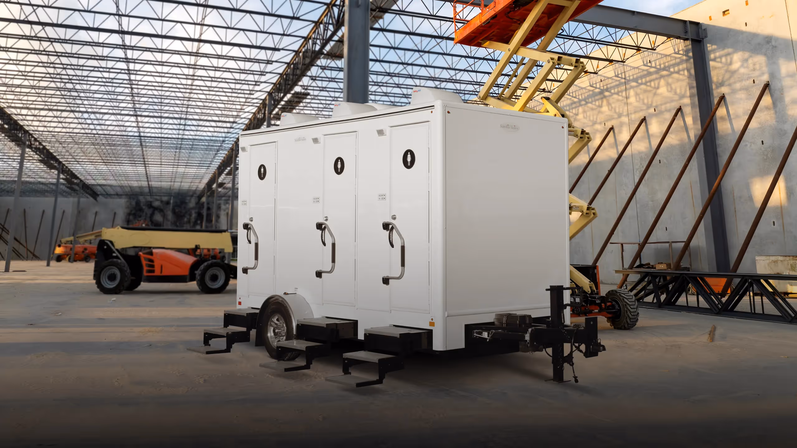 A 6x14' mobile restroom trailer with three doors in a construction setting.