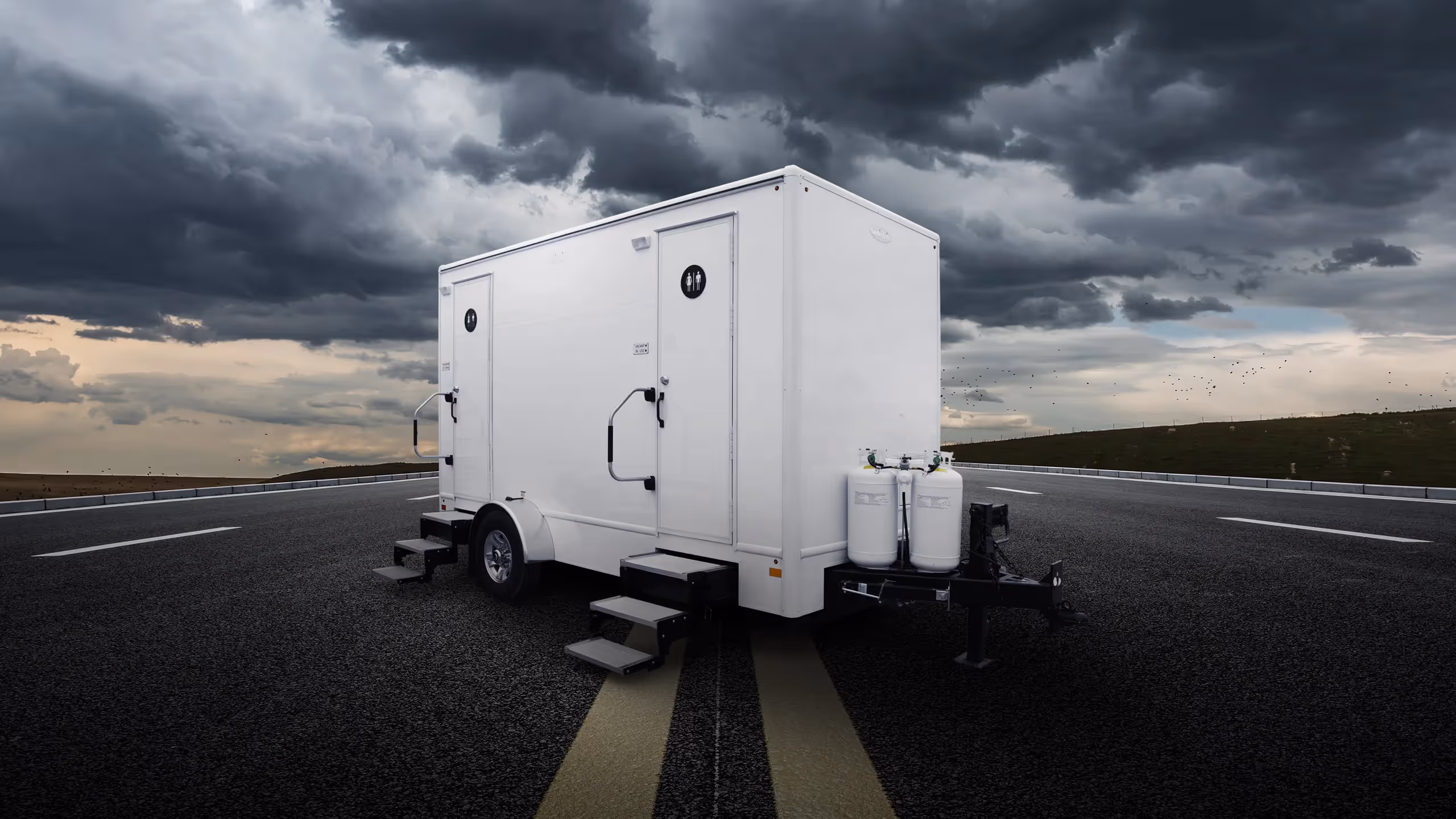 White 2-door combo shower unit on a road, with dark stormy clouds in the background.