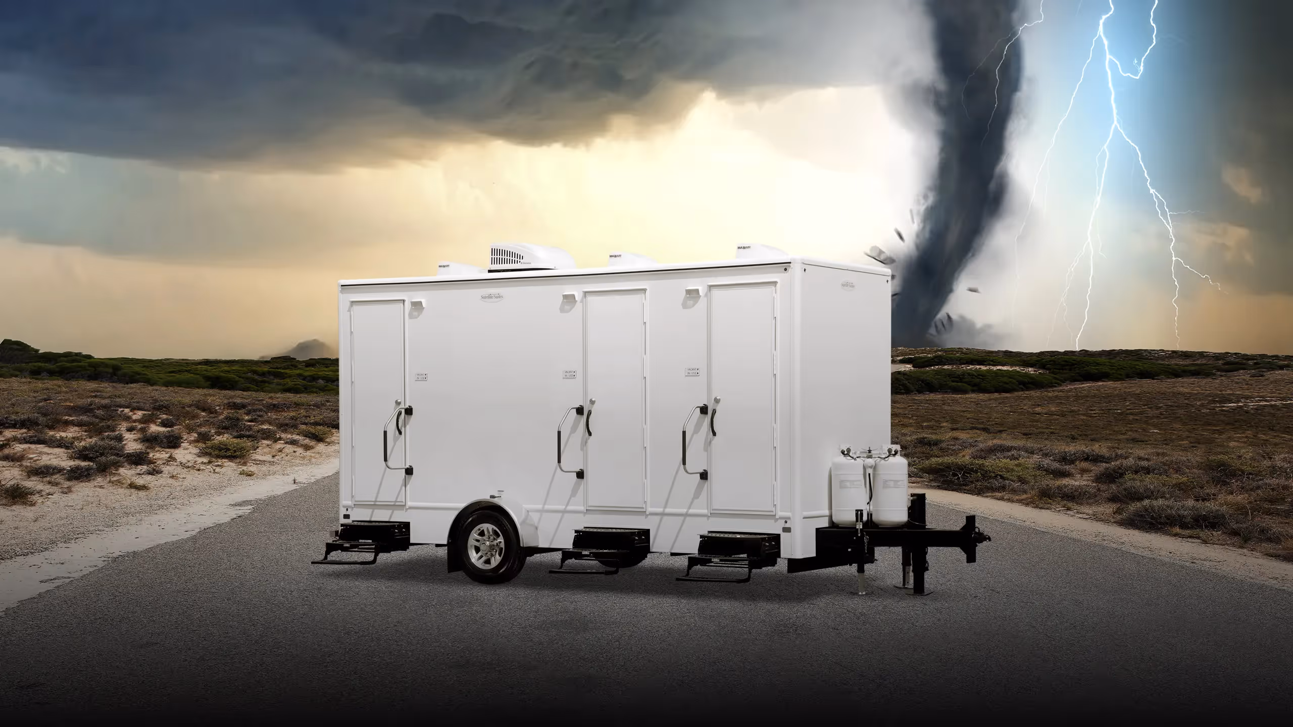 Three-station shower trailer on a road with a stormy sky and tornado in the background.