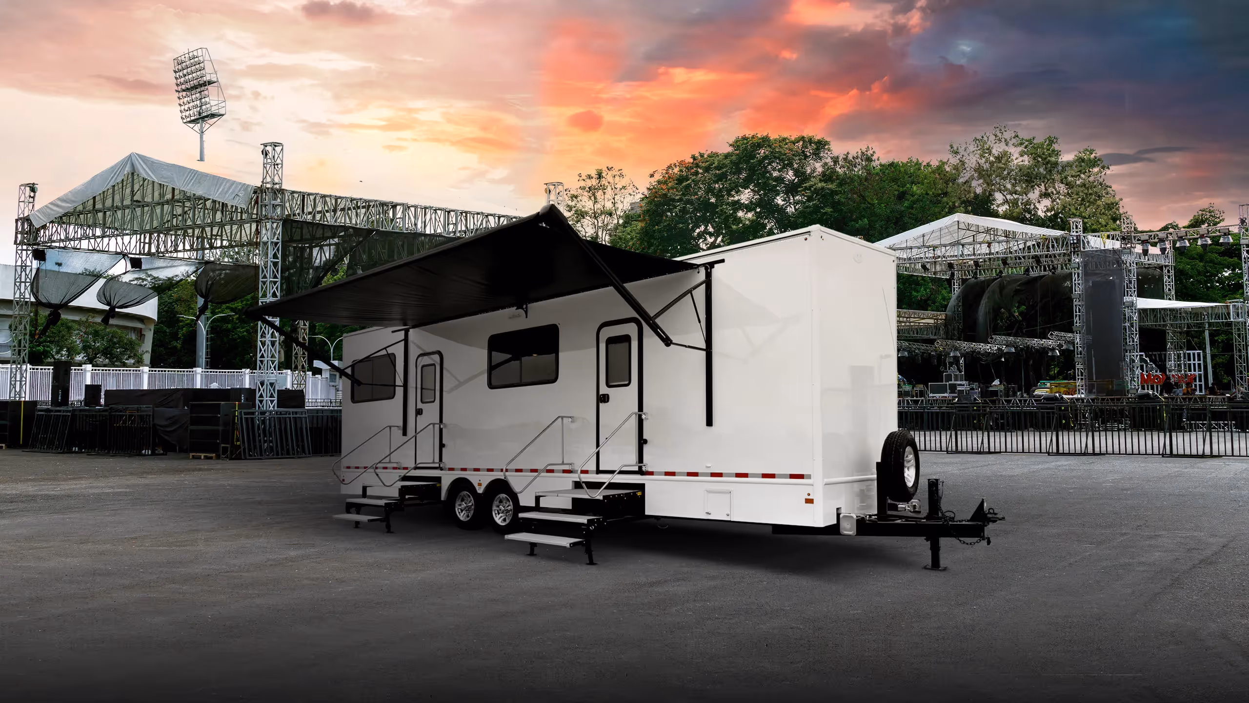 White 8x30' command center trailer set up outdoors near a stage under a dramatic sky.