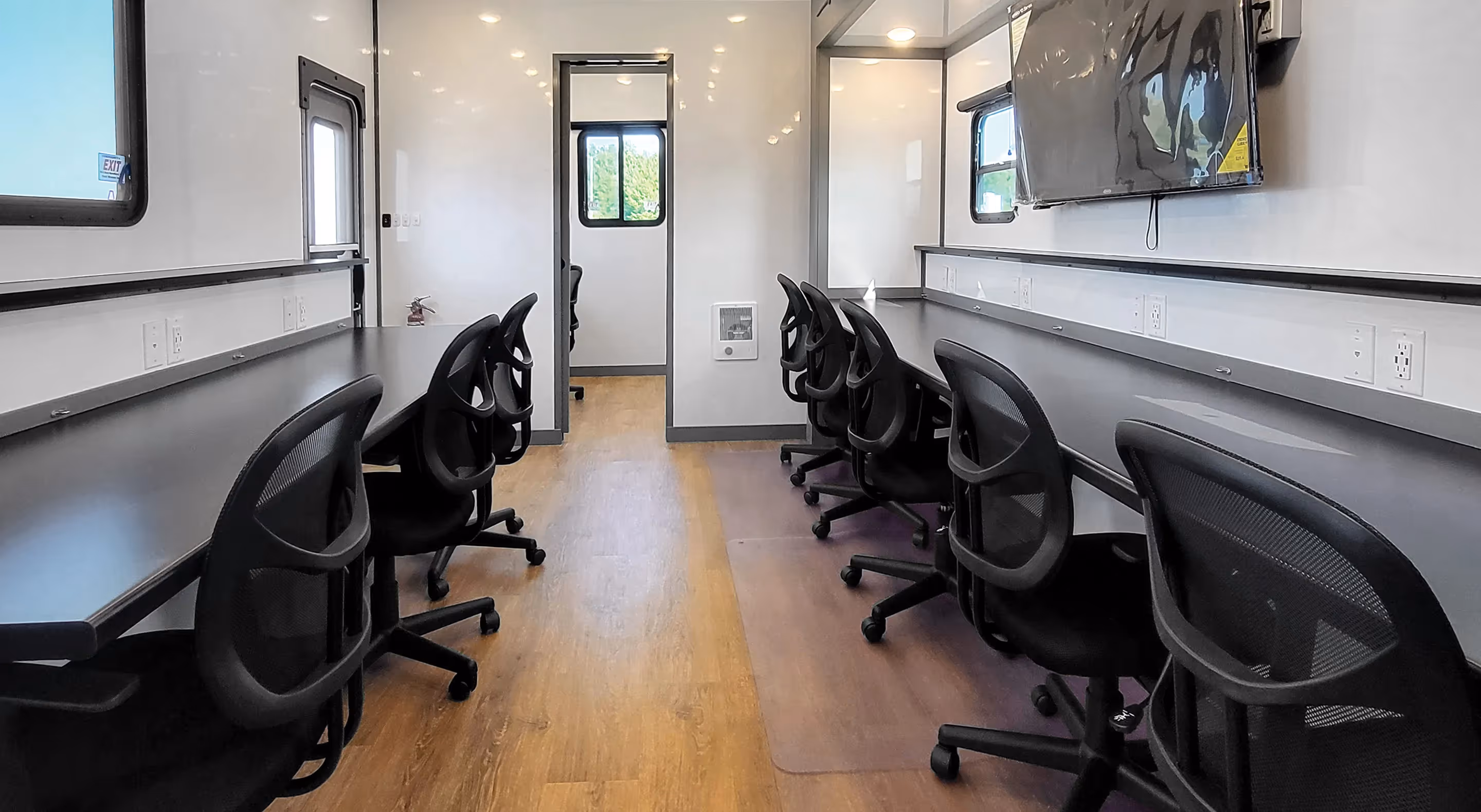 Interior of an 8x30' Command Center featuring desks, chairs, and a wall-mounted TV.