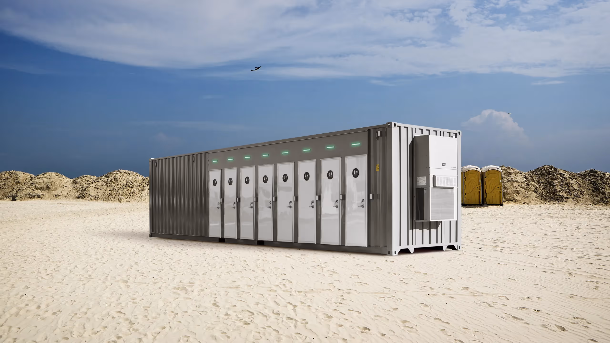 Container restroom unit with multiple enclosed stalls, set on a sandy landscape under a blue sky.