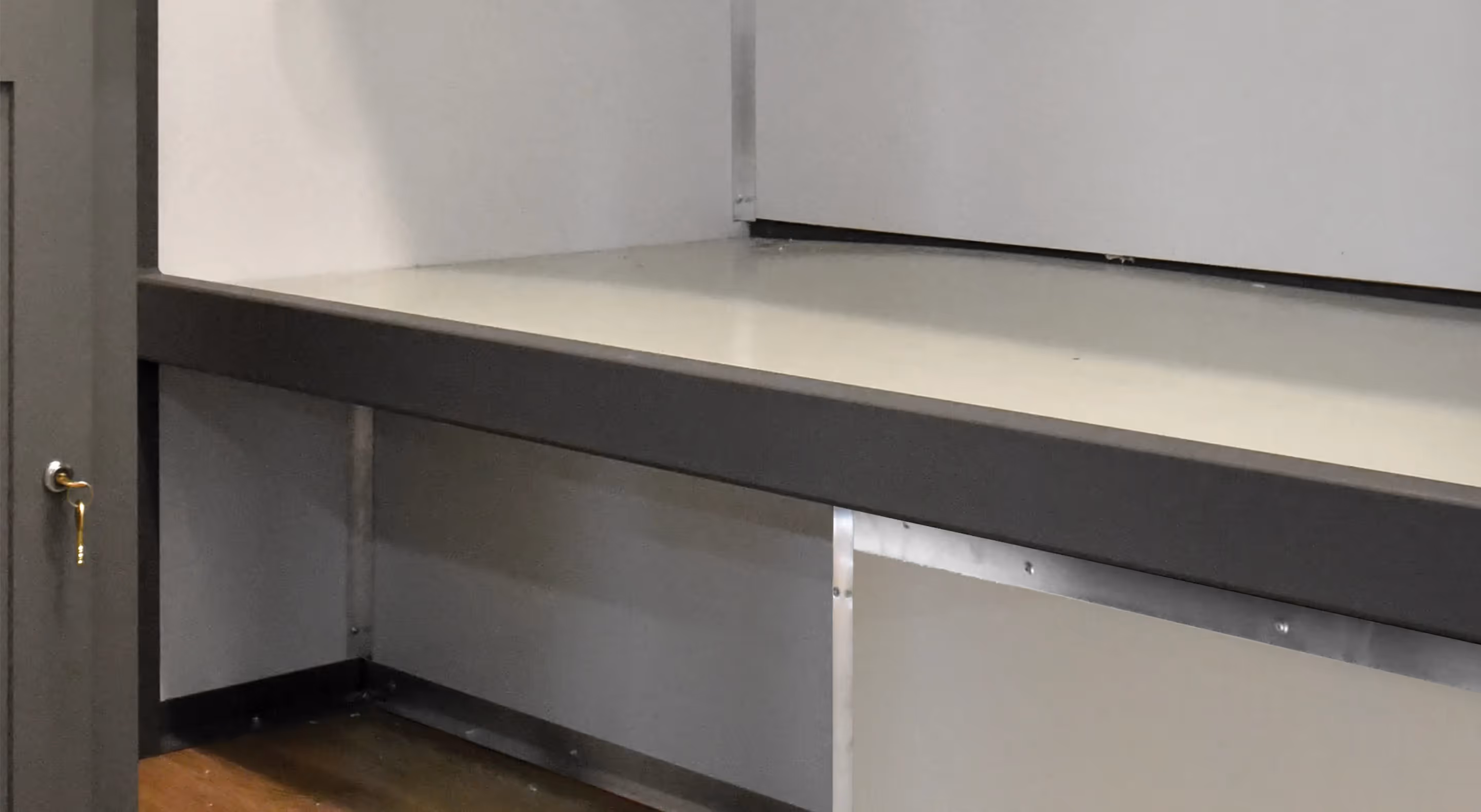 A minimalist bunk space with a gray bench and white wall panels, designed for privacy.