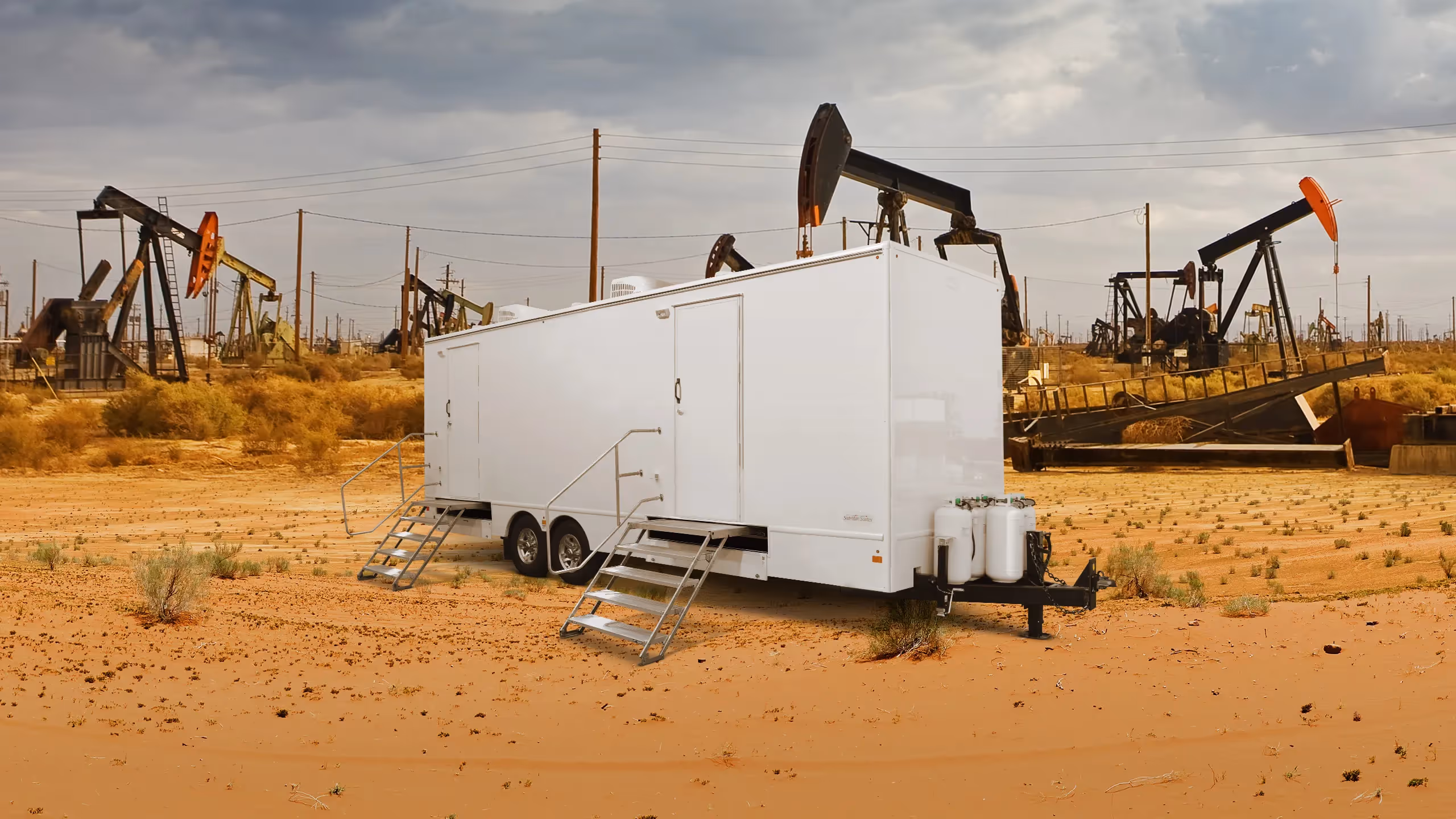 Laundry trailer with eight stations in a desert setting near oil rigs and sparse vegetation.