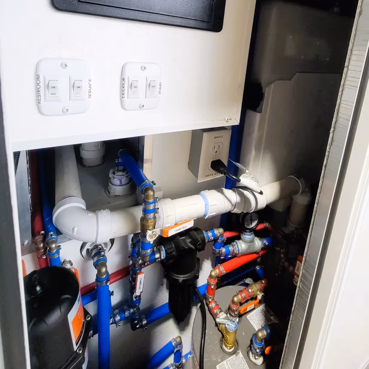 Compartment with pipes, valves, switches labeled restroom, service, exterior, plumb, and a service outlet.