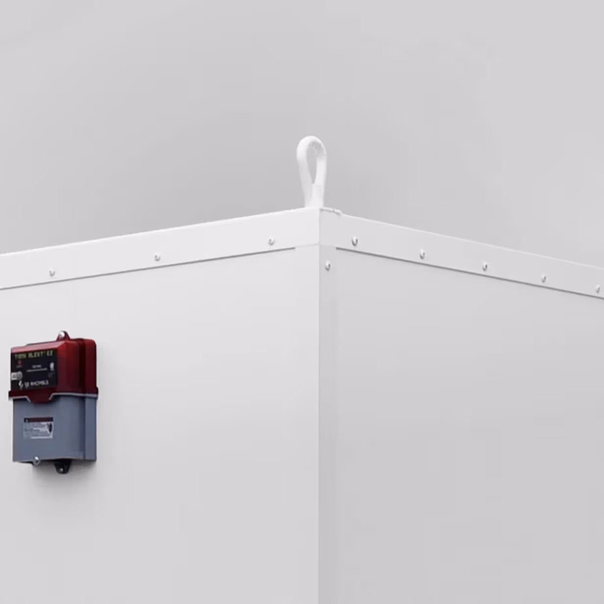 Corner of a white storage unit featuring built-in eye hooks and a mounted control box.