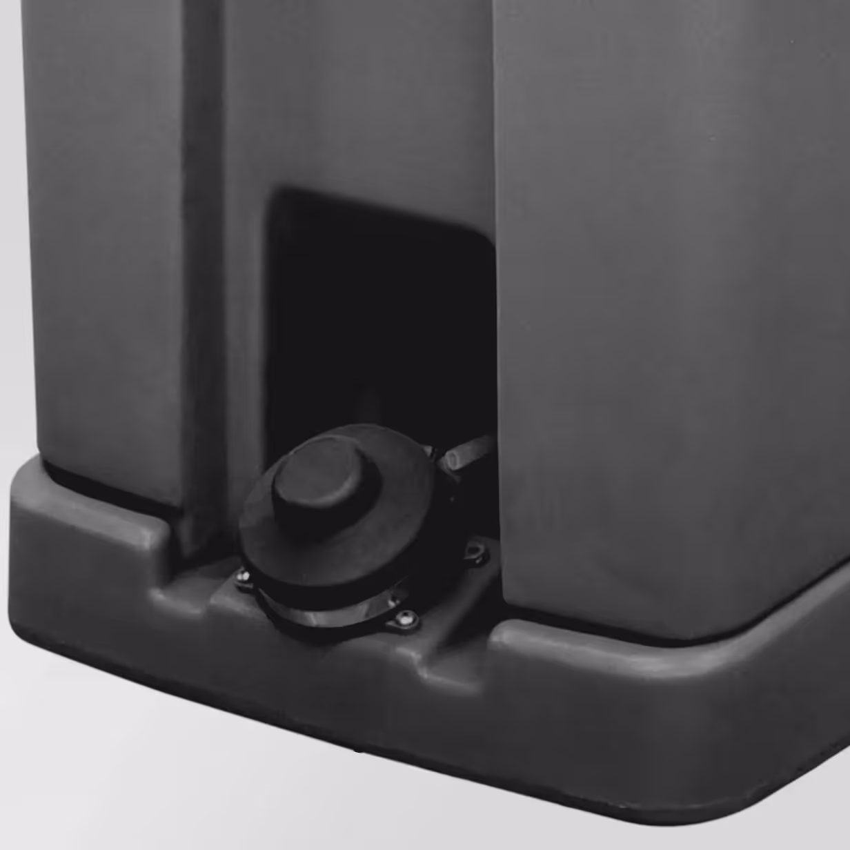 Close-up of the black foot pedal on the base of a large plastic device.