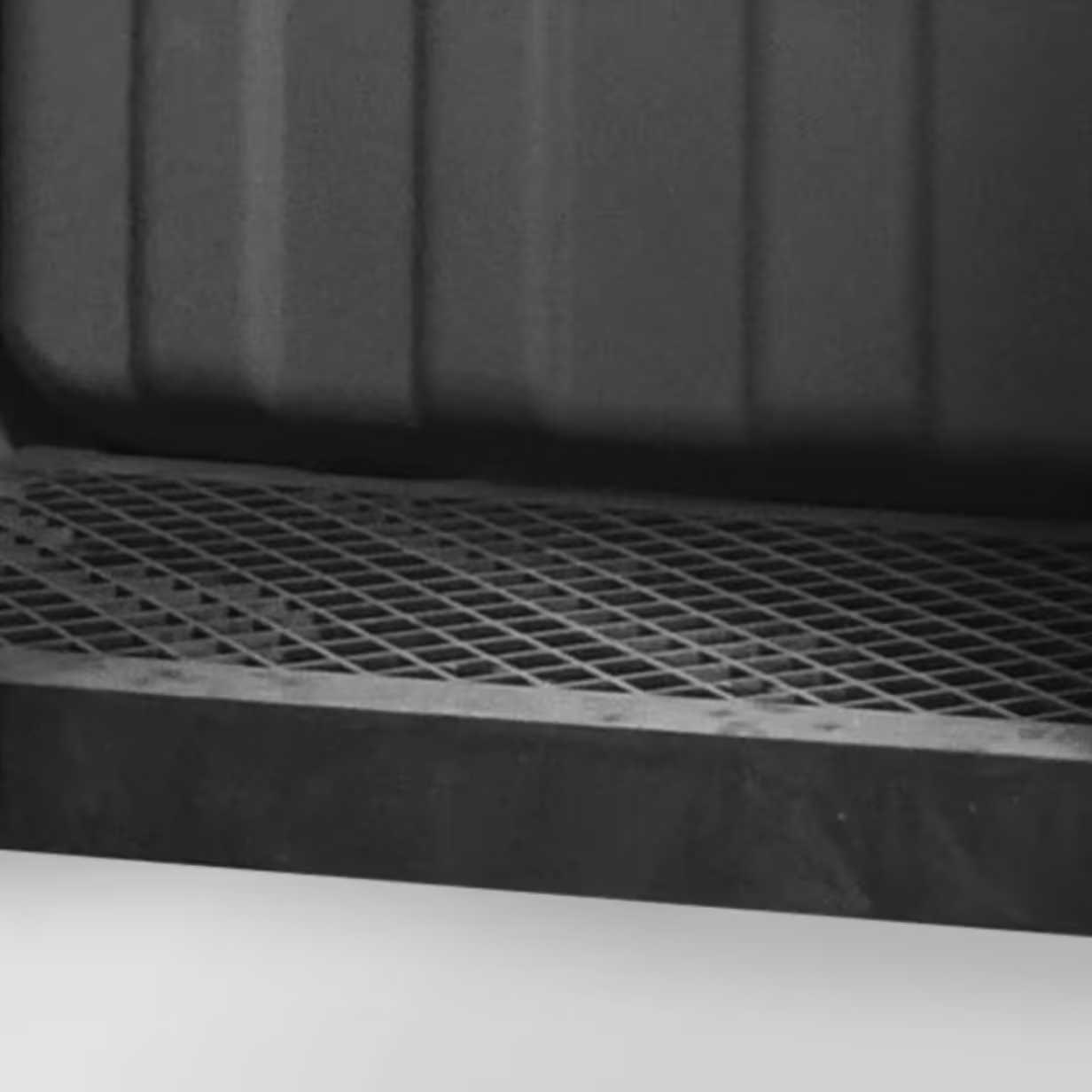 Close-up of black metal grid plate with a frame and a dark ridged surface behind it.