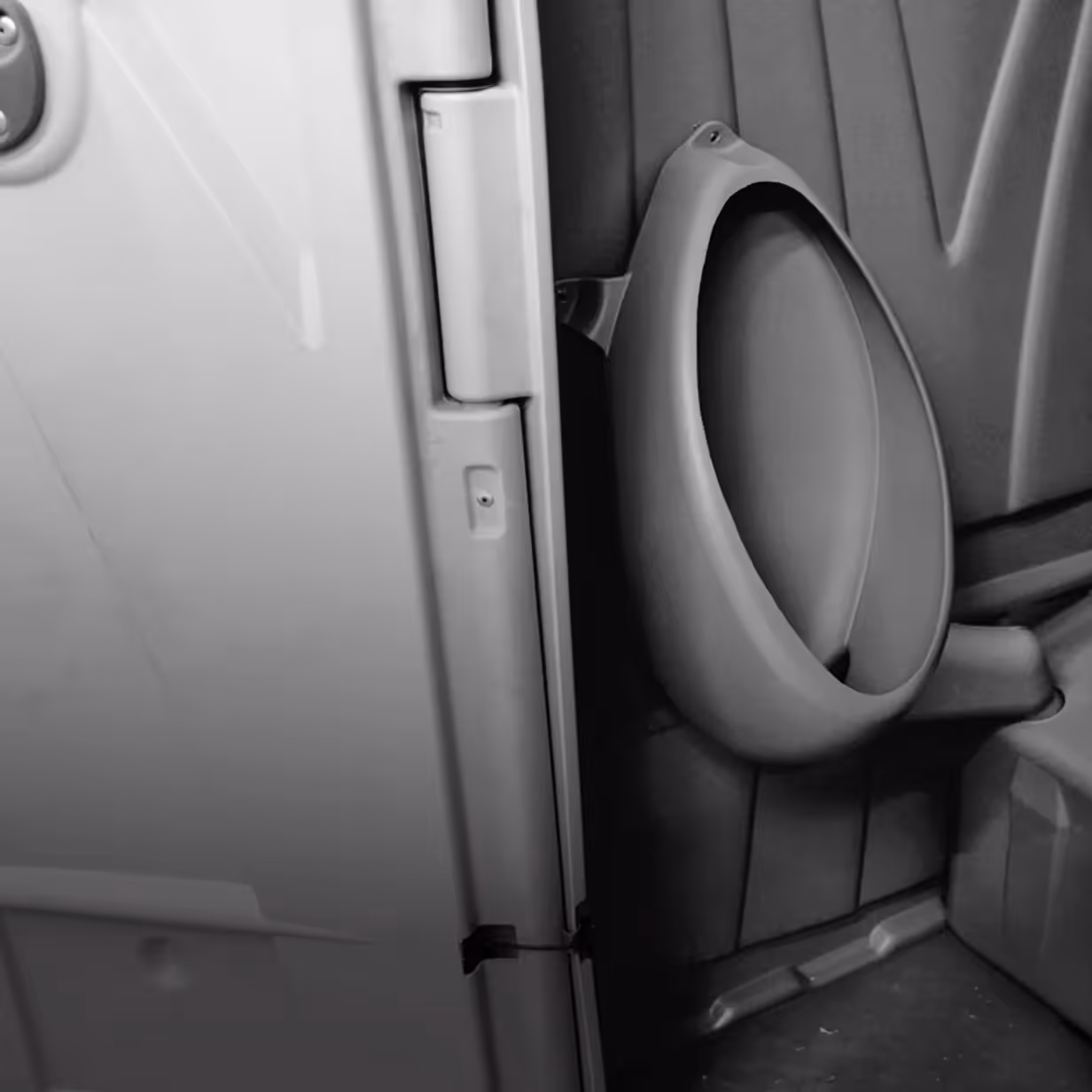 Close-up of a gray urinal mounted on a textured wall inside a restroom.