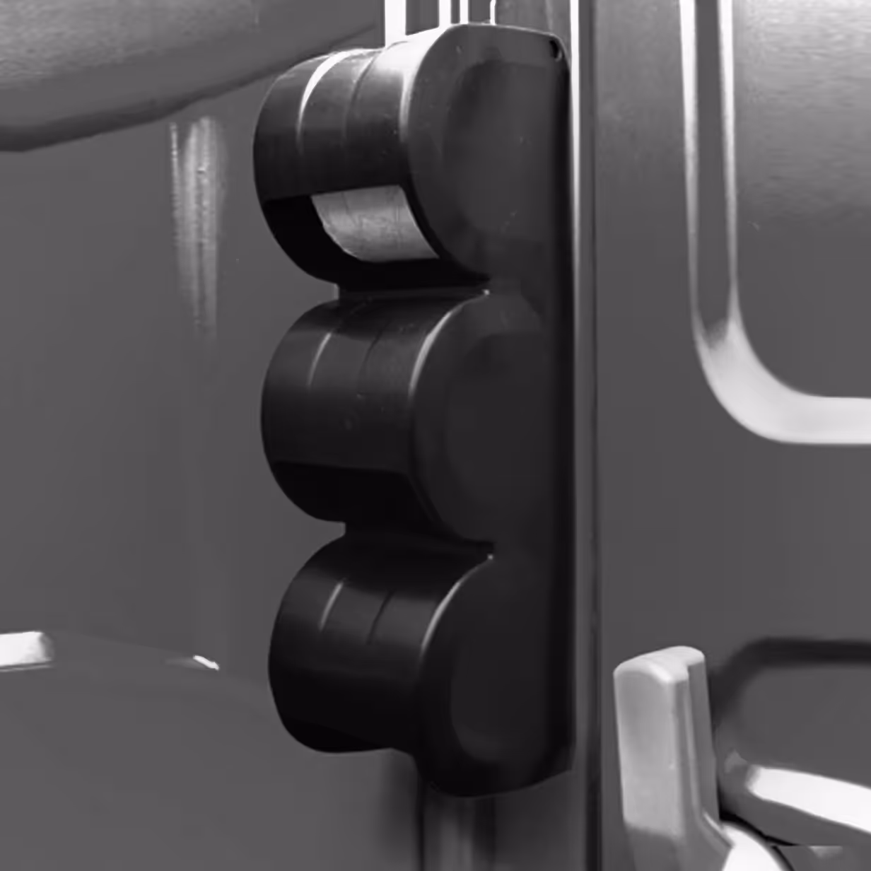 Close-up of a black vertical paper guard with three rounded sections on a metallic surface.