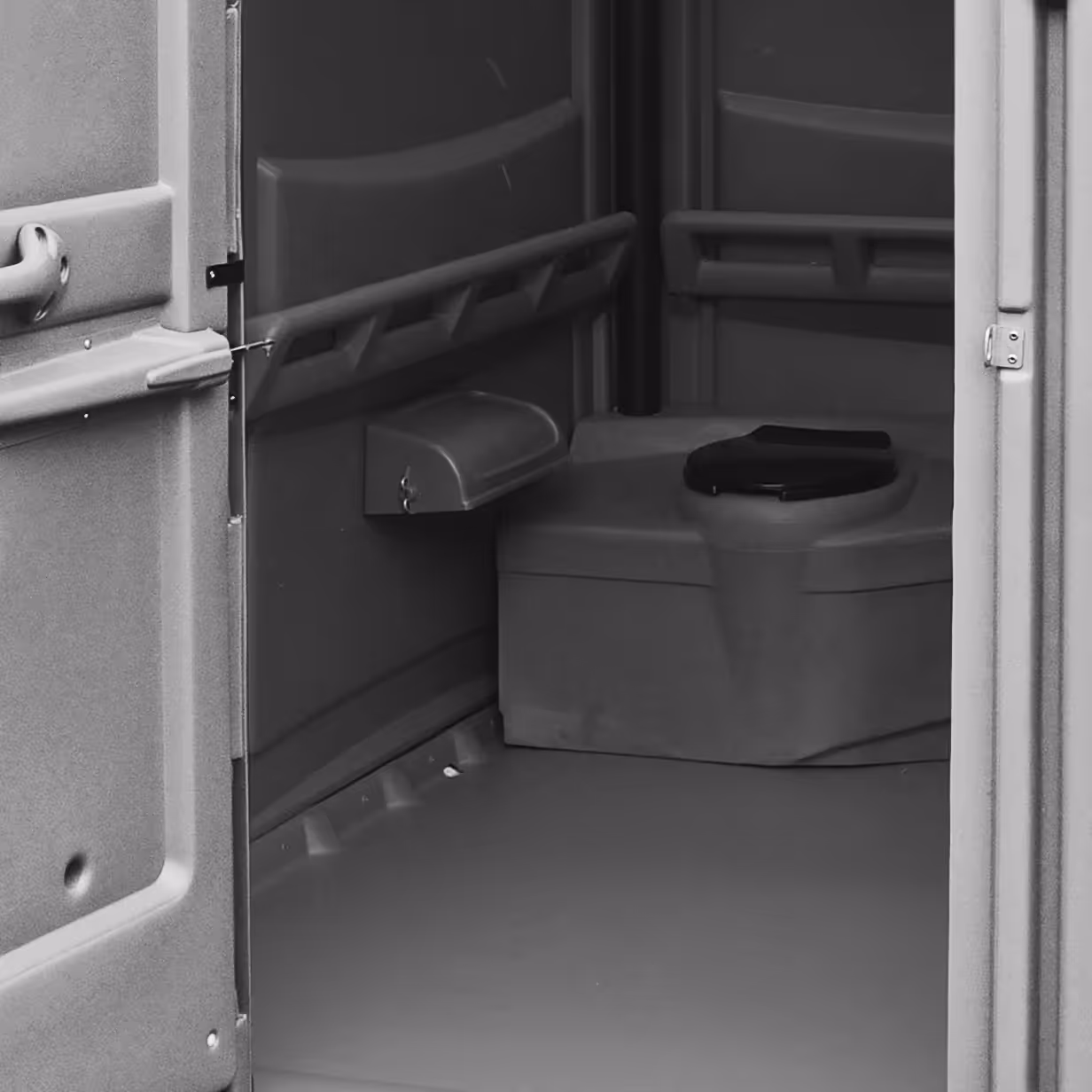 Interior of a portable toilet showing the toilet seat, handrails, and door handle.