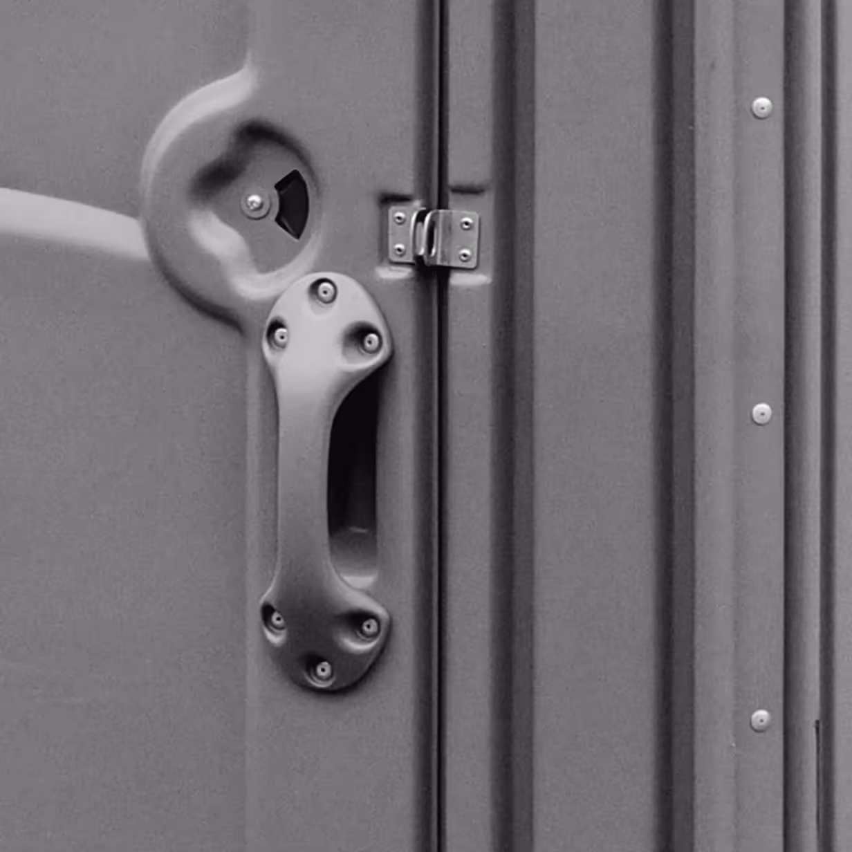 Close-up of gray plastic door handle and locking mechanism on a portable restroom door.