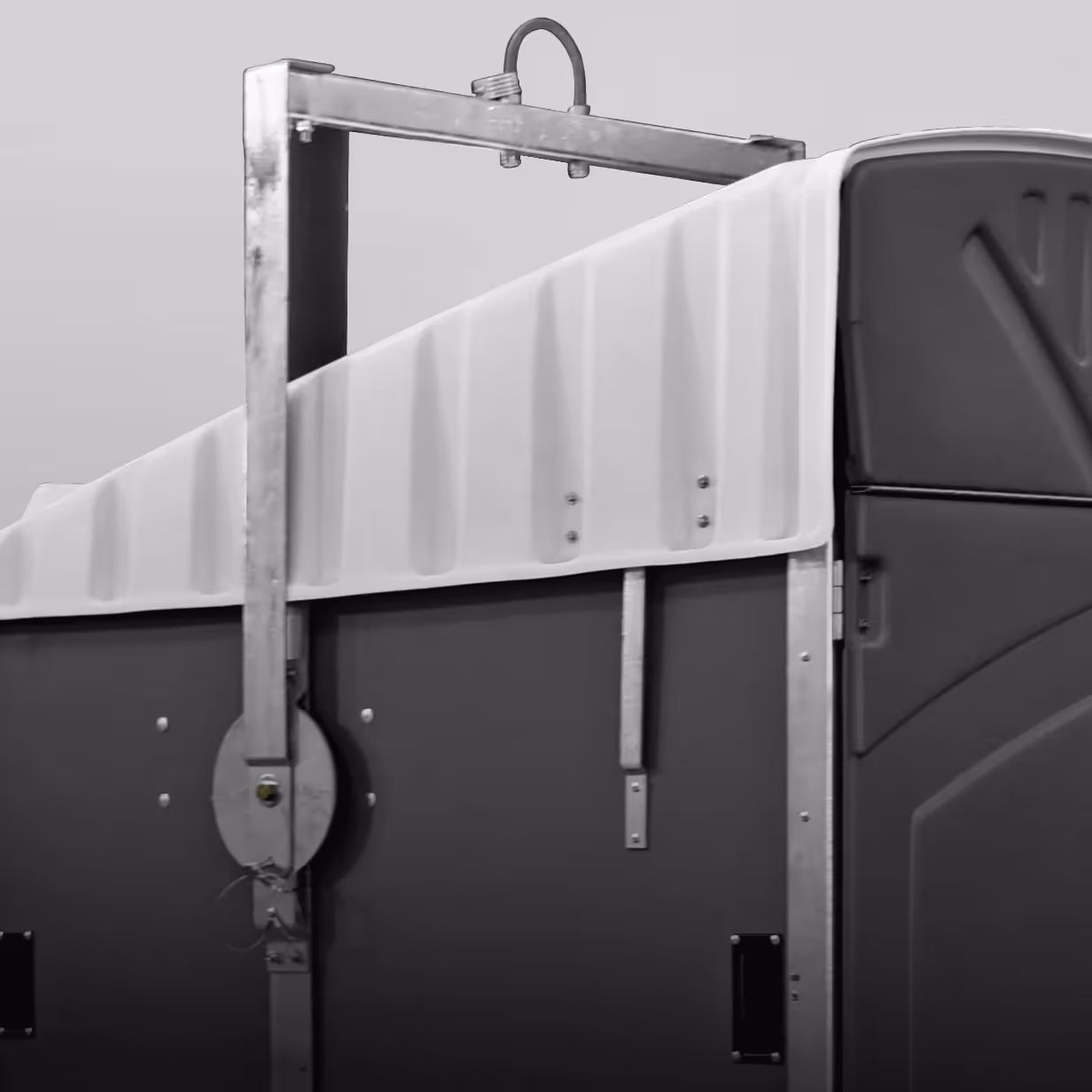 Metal lift kit mounted on side of a portable restroom with a white top and dark gray body.