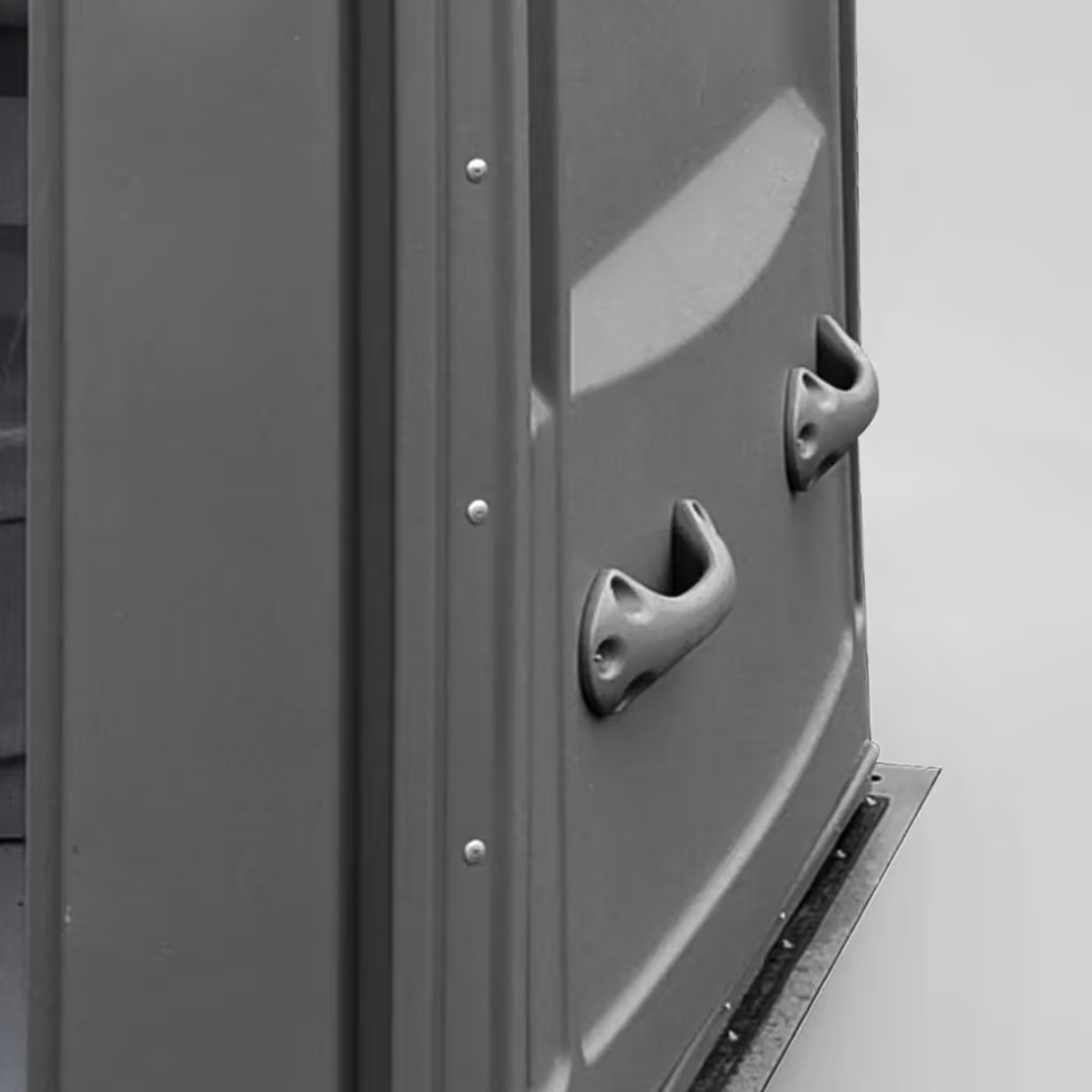 Two curved handles attached vertically on the gray side wall of a portable toilet.