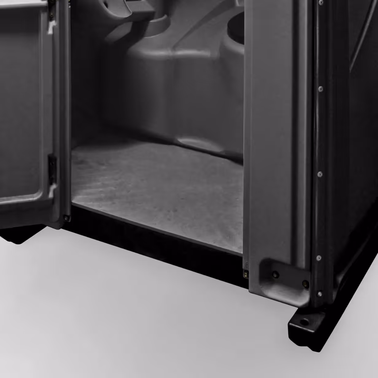 Close-up of the open bottom part of a dark plastic enclosure with a textured base and support legs.
