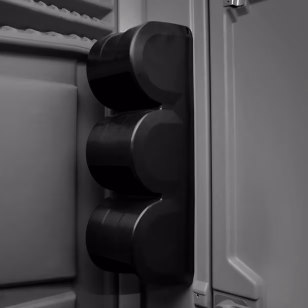 Close-up of a vertical paper guard with three rounded black bumpers attached to a cabinet door.
