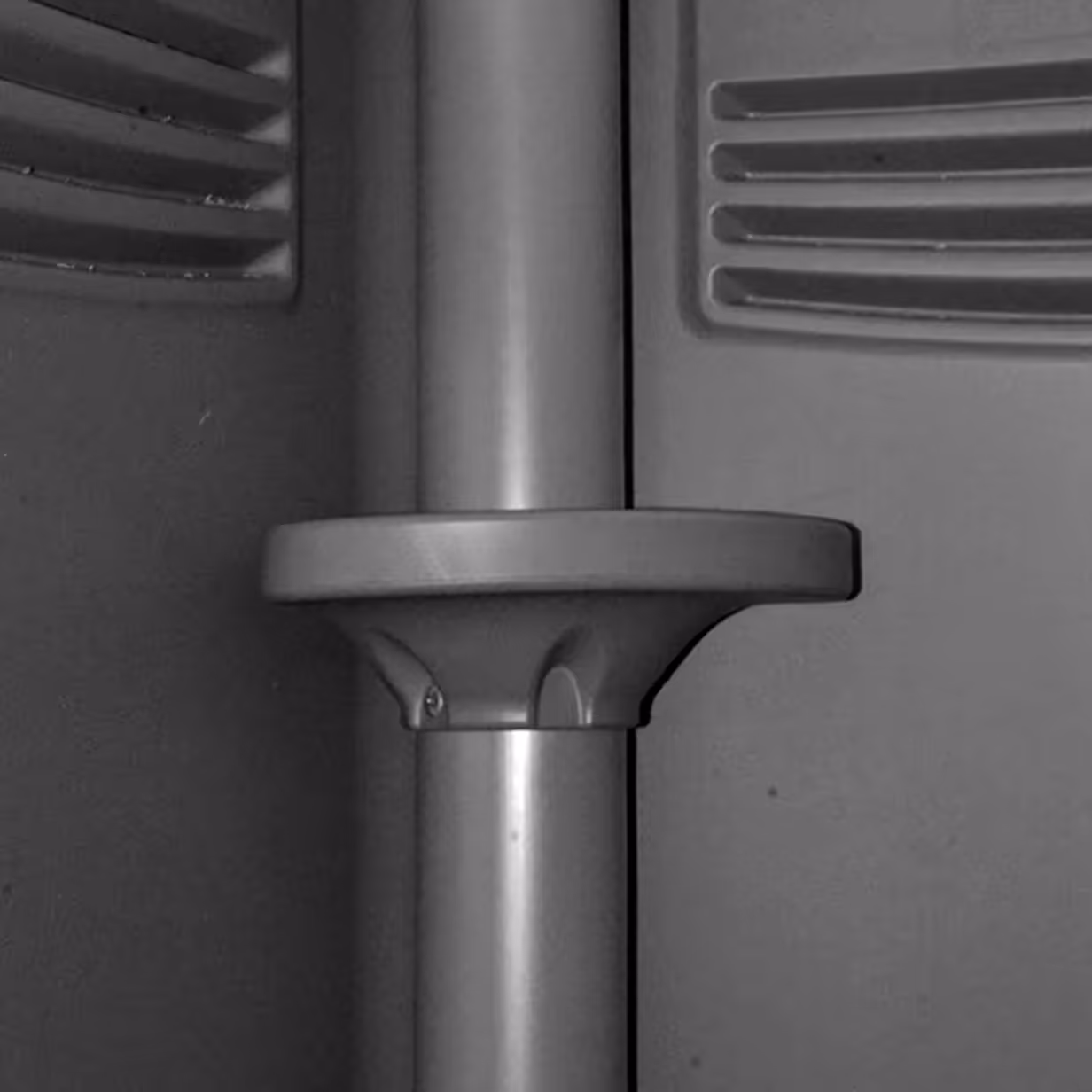 Close-up of a vertical gray metal pole with a round horizontal shelf attached.