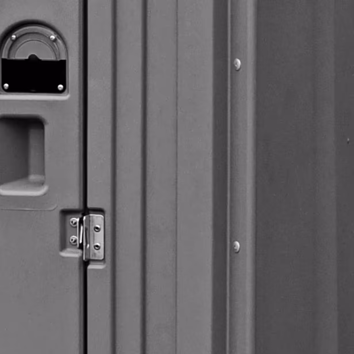 Close-up of gray plastic door with handle, latch, and two frame-mounted rivets.