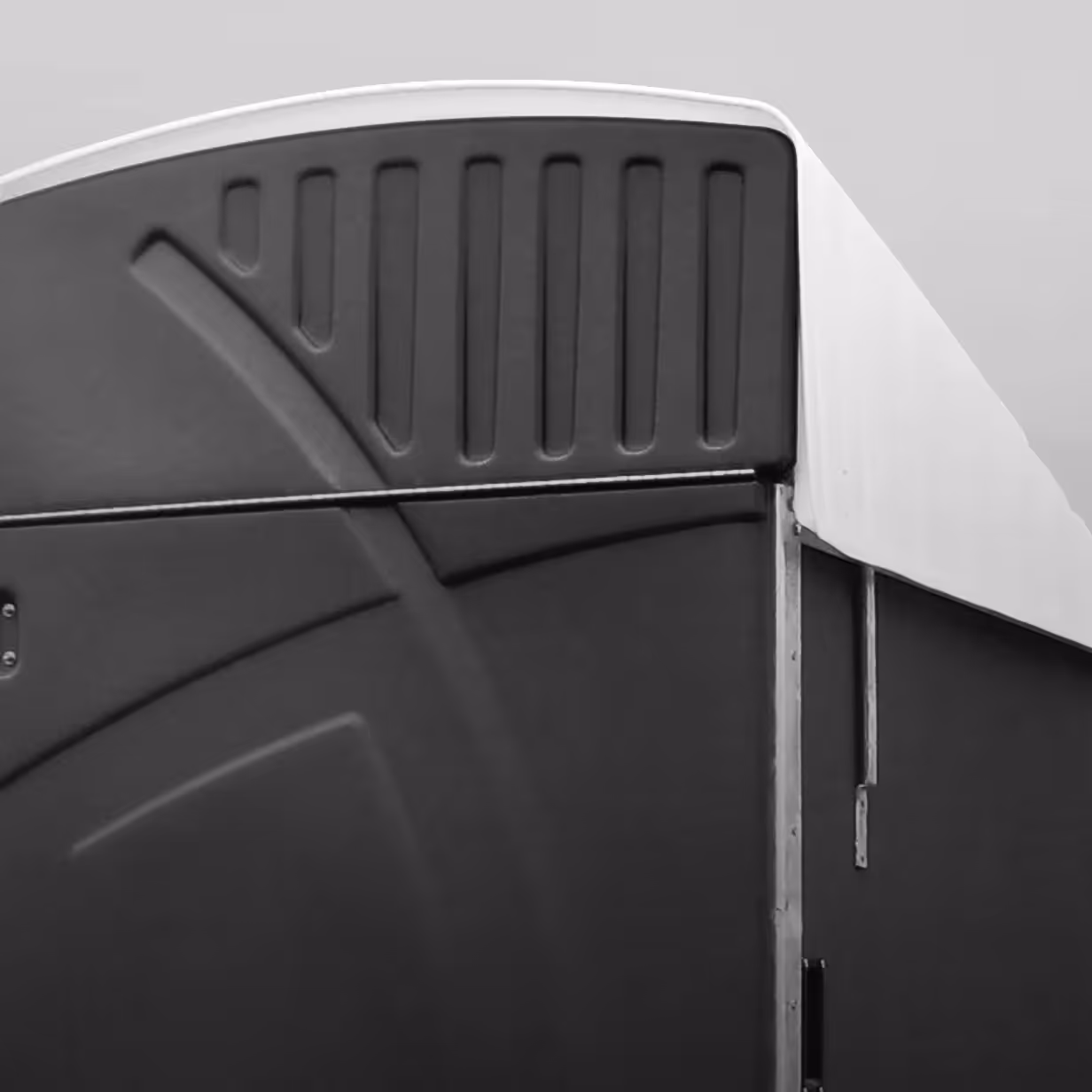 Close-up of top corner of a black and white plastic or metal structure with textured patterns.