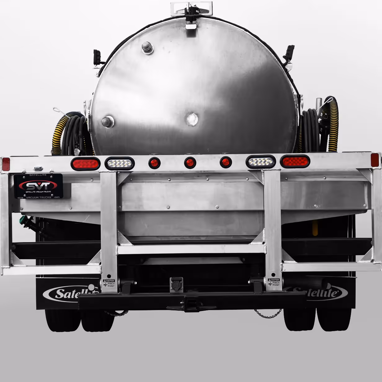 Rear view of a metal vacuum truck tank with yellow-black hoses coiled on each side.