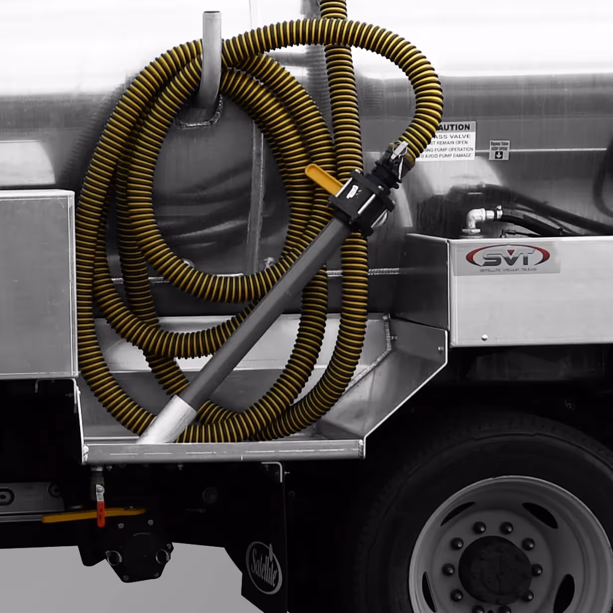 Yellow and black coiled hose attached to a metal truck with visible tire and caution signs.