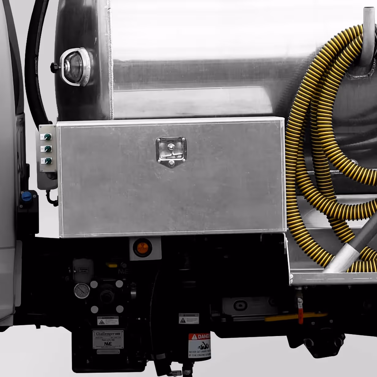 Side view of truck with metallic toolbox, yellow coiled hose, and hydraulic components.