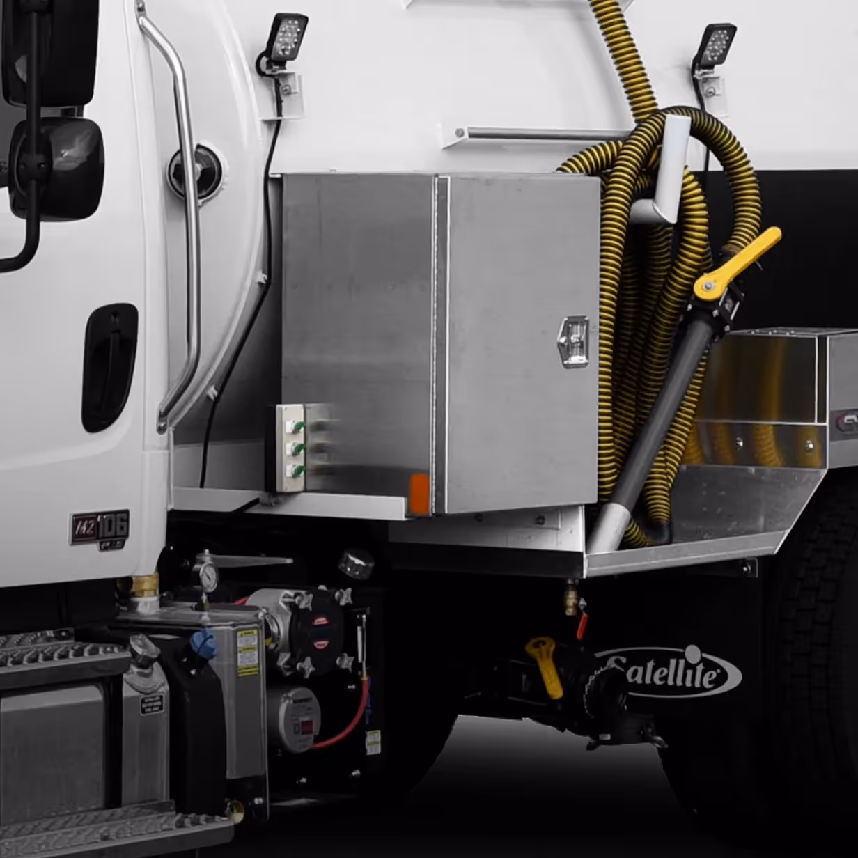 Close-up of a white truck with stainless steel storage box and coiled yellow hose attached.