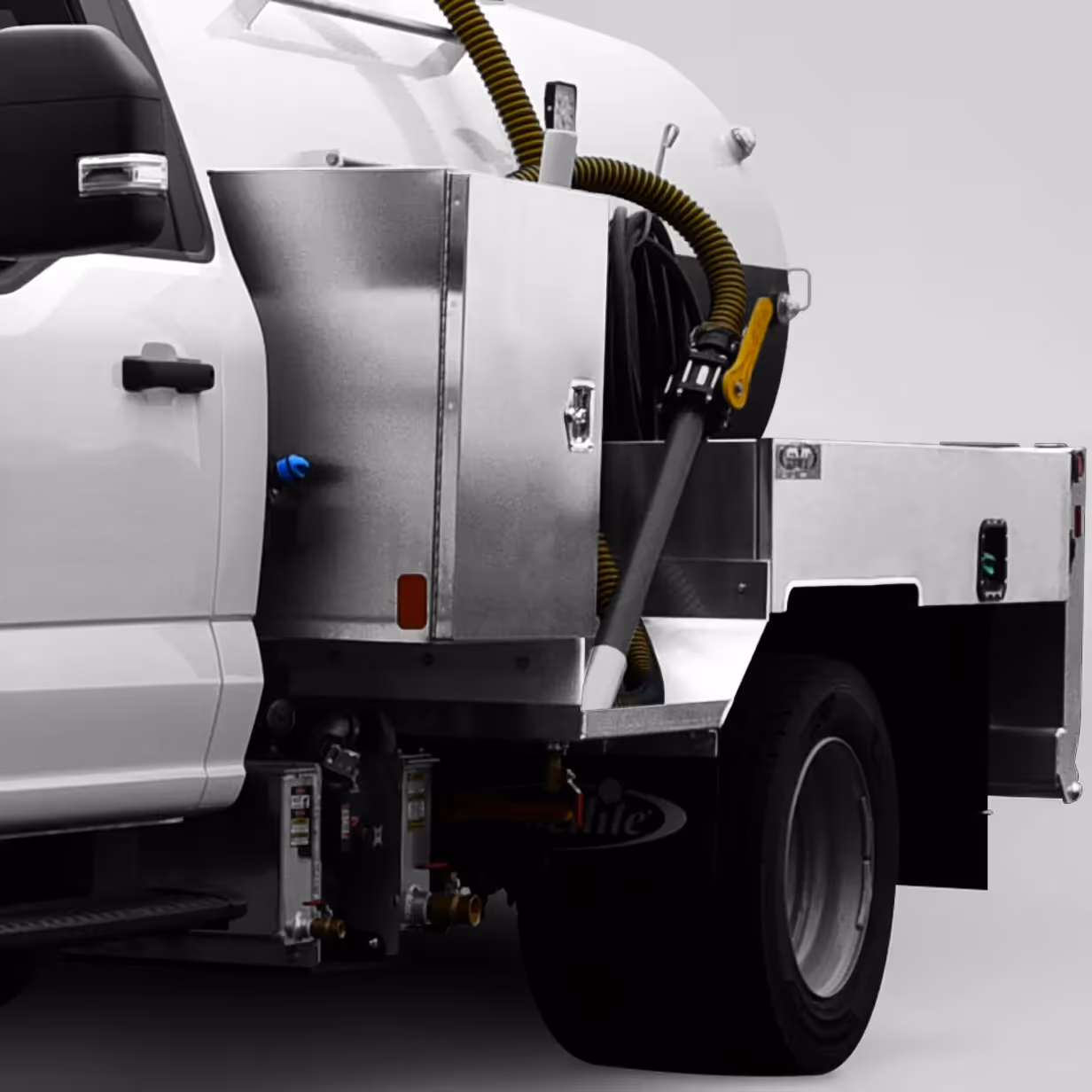 Side view of a white truck with stainless steel utility cabinets and yellow hose on the back.