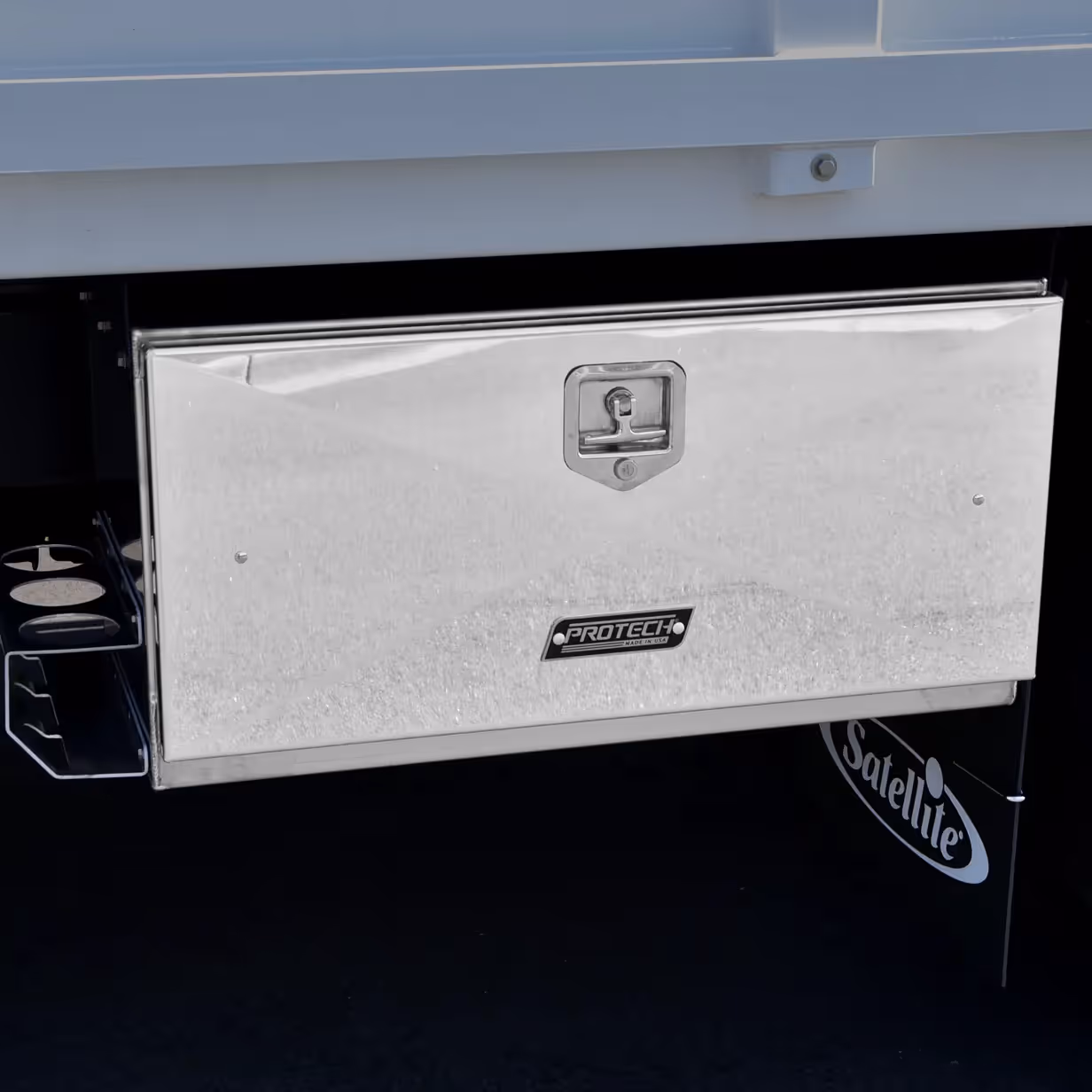 Rectangular stainless steel lockable storage box with ProTech label mounted under a vehicle.