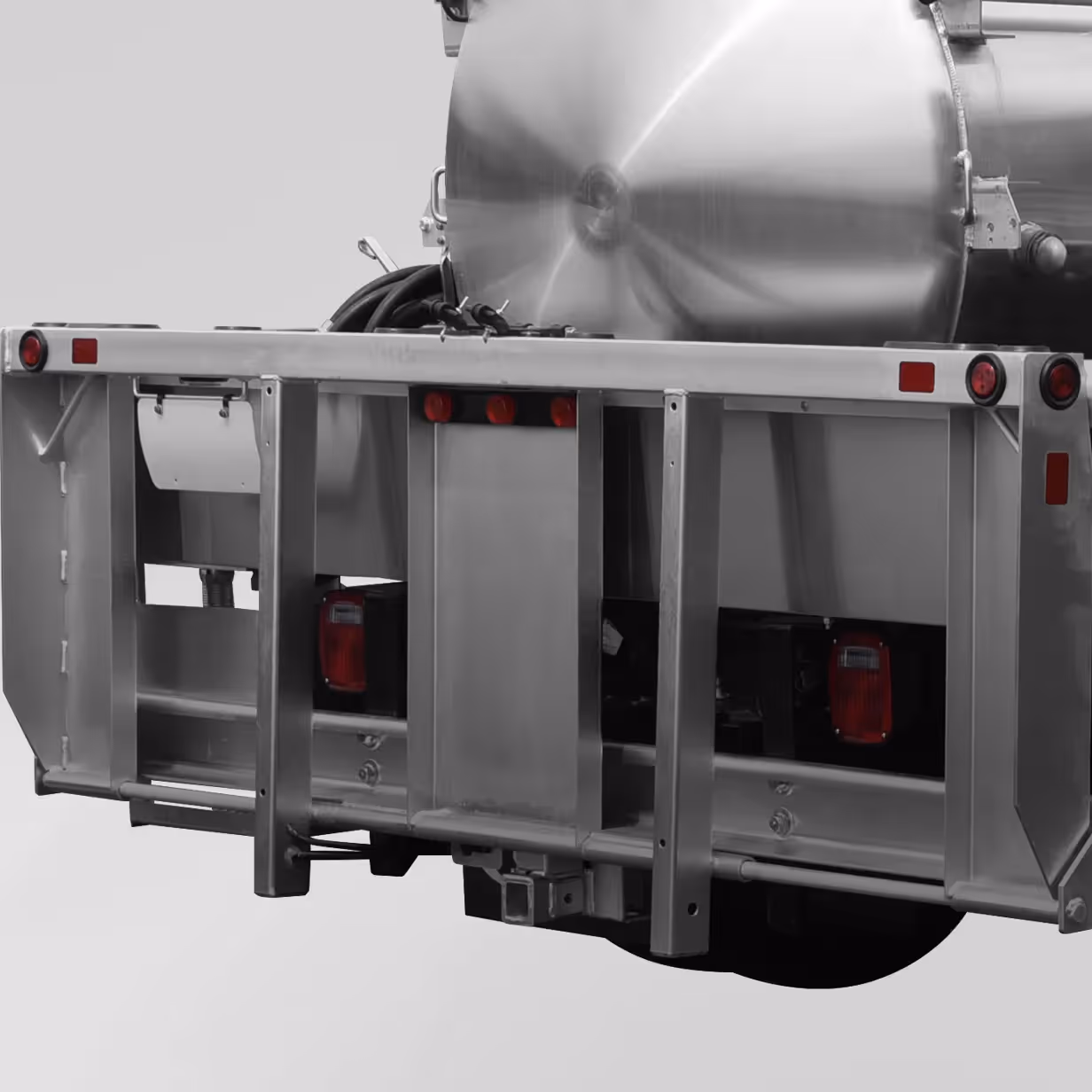 Close-up of the rear section of a shiny silver industrial tanker trailer with red lights.