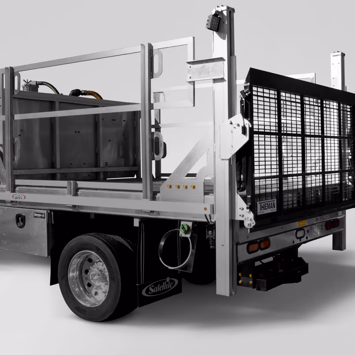 Rear side view of a flatbed truck with metal railing and a black mesh tailgate.