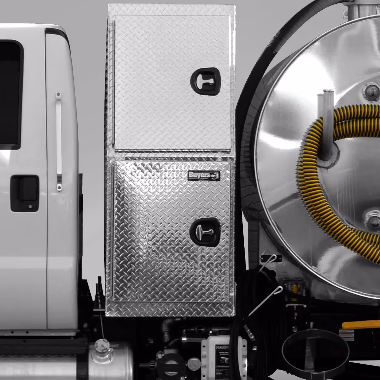 Side of a white truck with two diamond plate storage compartments and part of a stainless steel tank with a yellow hose.