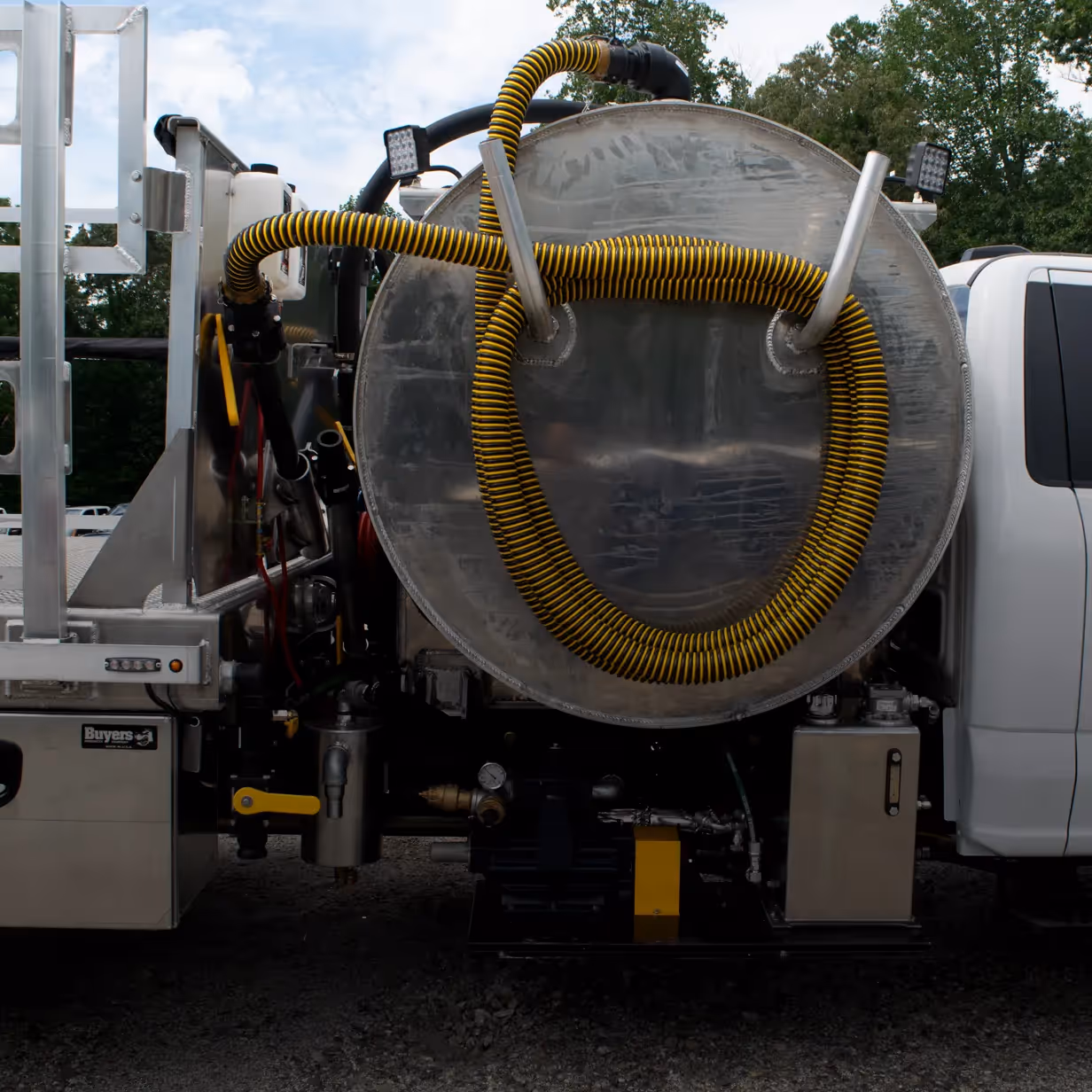 Back view of a service truck tank with yellow and black coiled hose attached.