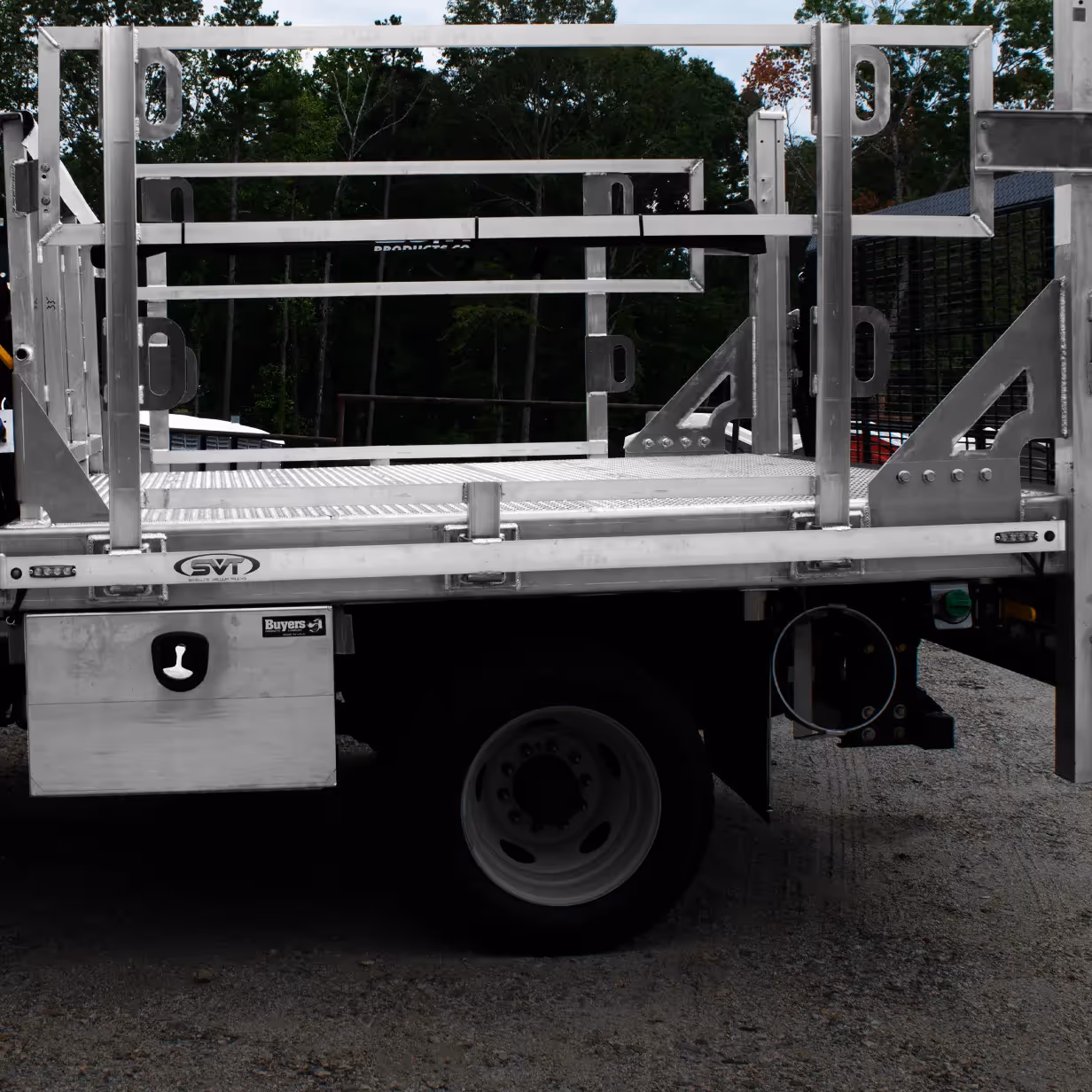 Side view of a flatbed truck with metal frame and storage box under the bed.