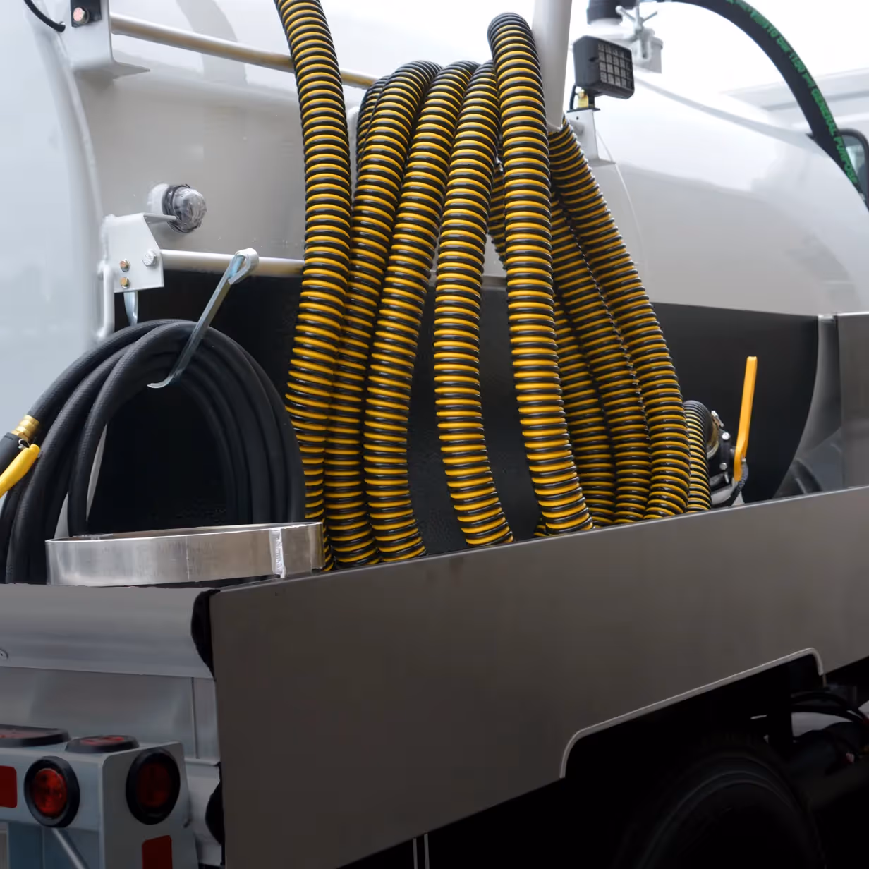 Coiled black and yellow hoses mounted on the side of a white service truck.