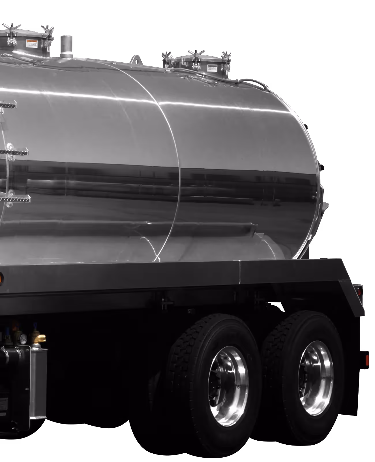 Silver stainless steel tank trailer with dual rear axles and multiple top access hatches.