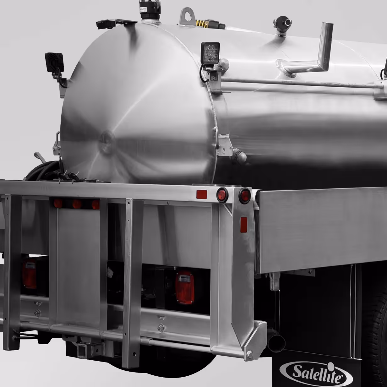 Rear view of a metallic stainless steel tank mounted on a truck with safety lights and Satellite mudflap.