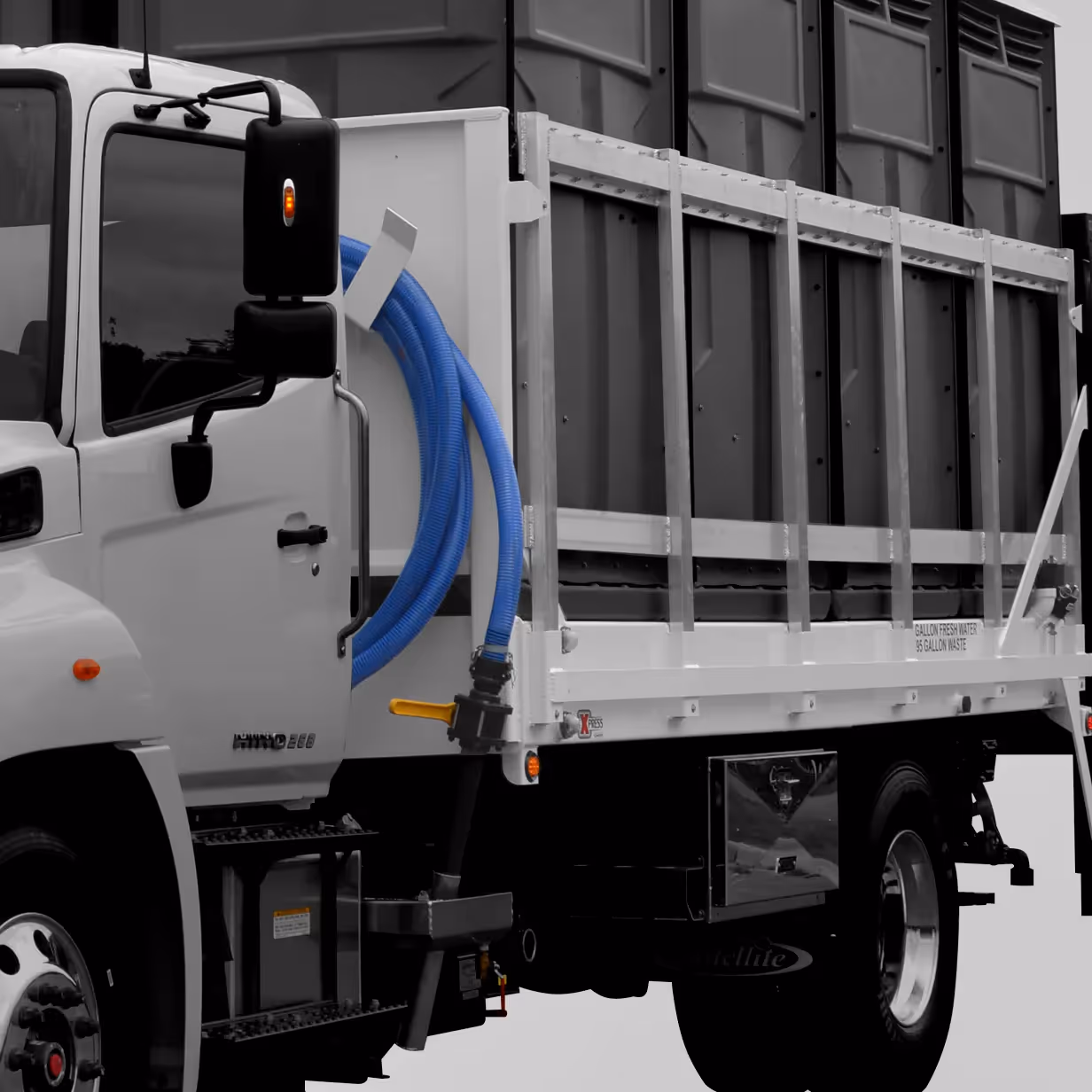 Side view of a white service truck with a blue hose coiled on the side and large storage compartments.