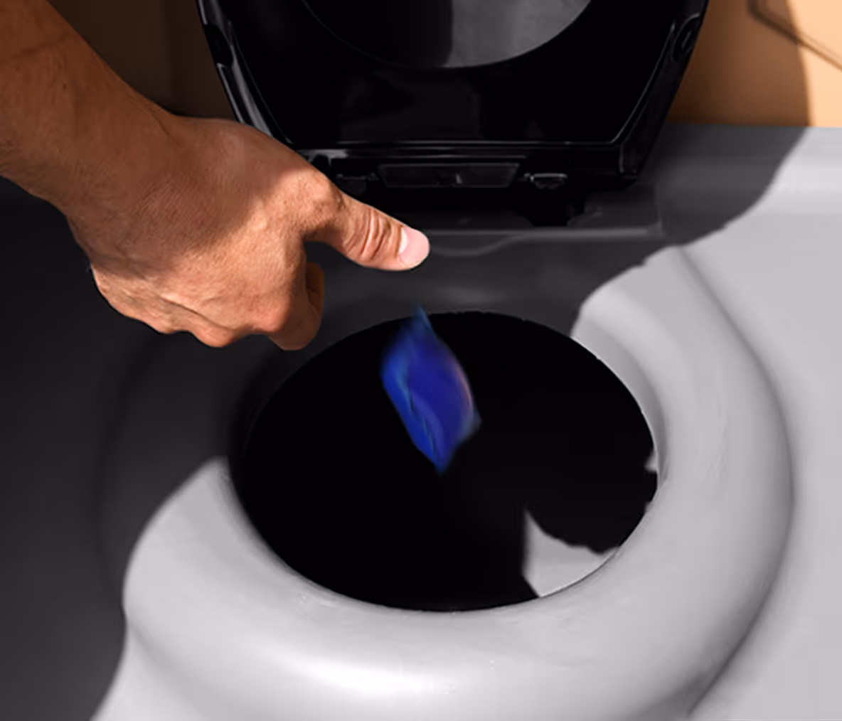 A hand drops a blue cleaning pod into the toilet bowl's opening.