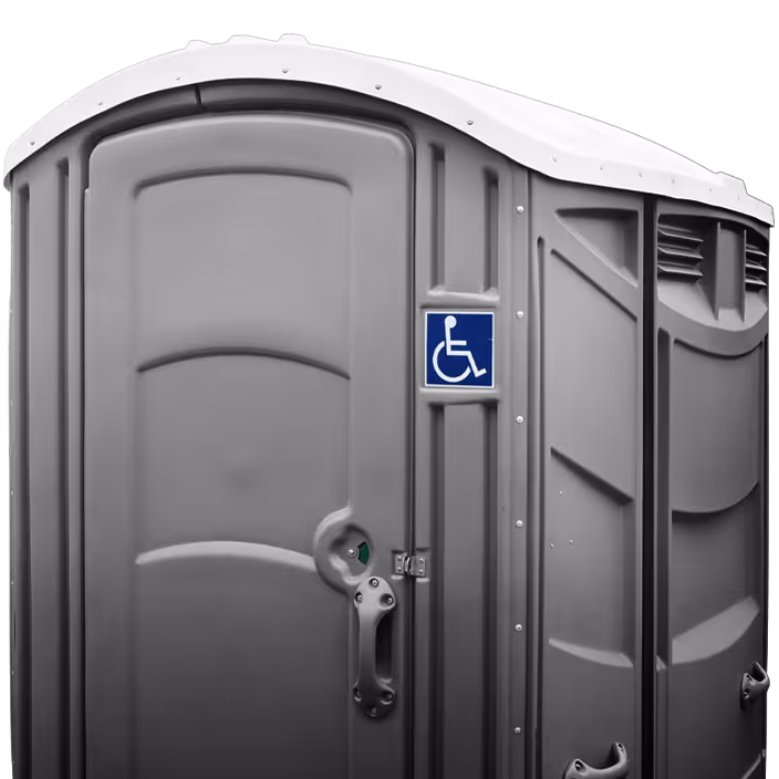 Gray portable restroom with a blue wheelchair accessibility sign on the door.