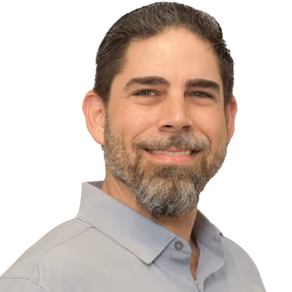 Smiling man with dark hair and beard wearing a light gray collared shirt.