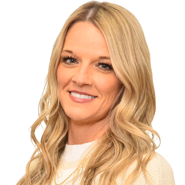 Smiling woman with long blonde wavy hair wearing a white sweater and gold chain necklace.