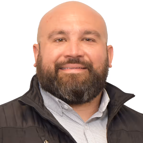 Smiling bald man with a beard wearing a black jacket and a light-patterned shirt.