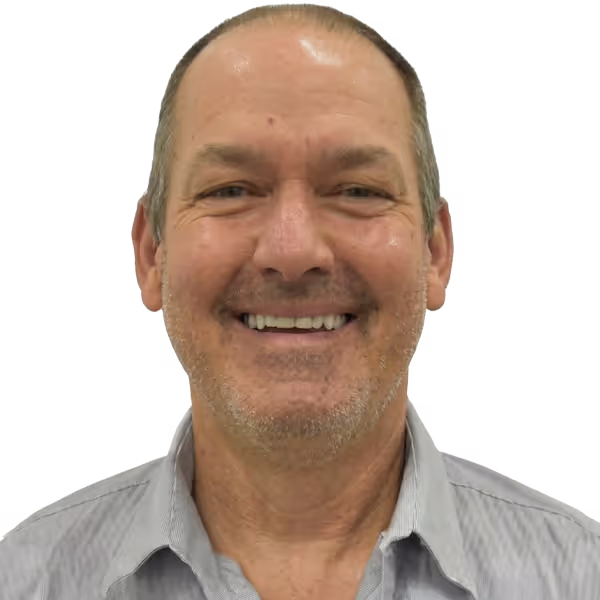 Smiling middle-aged man with short hair and stubble wearing a light gray collared shirt.