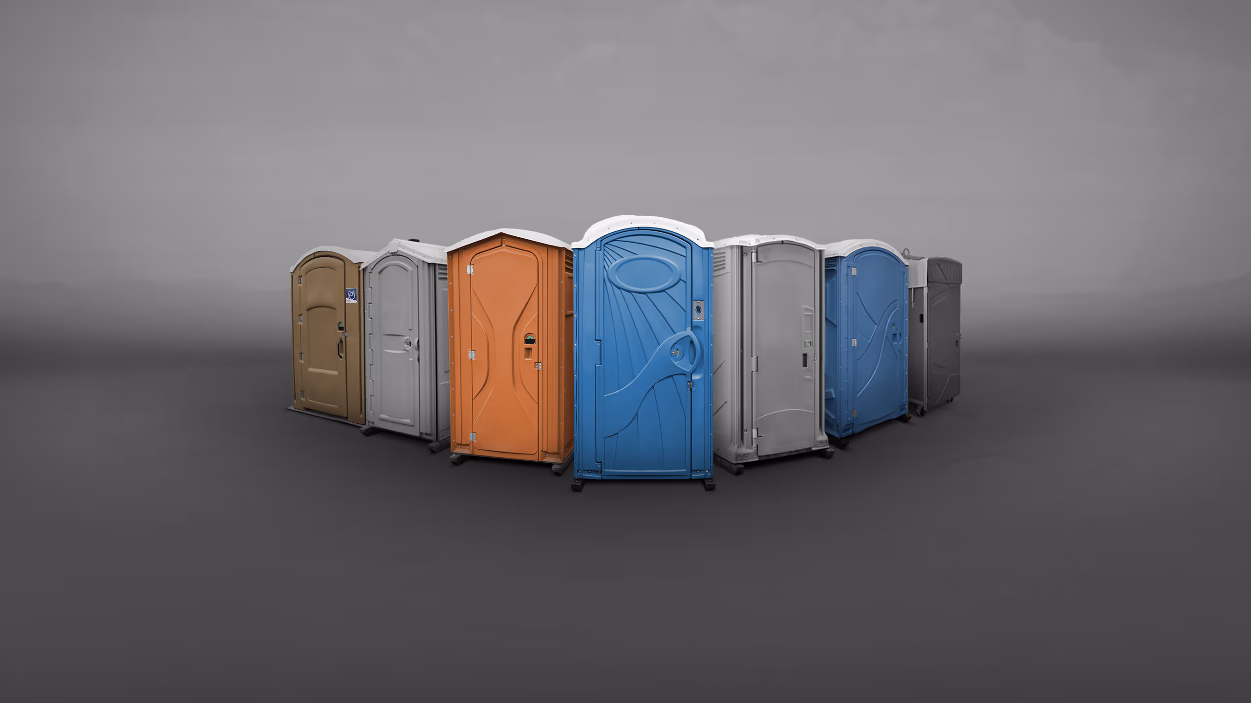 A series of portable toilets in various colors arranged in a circular formation on a gray