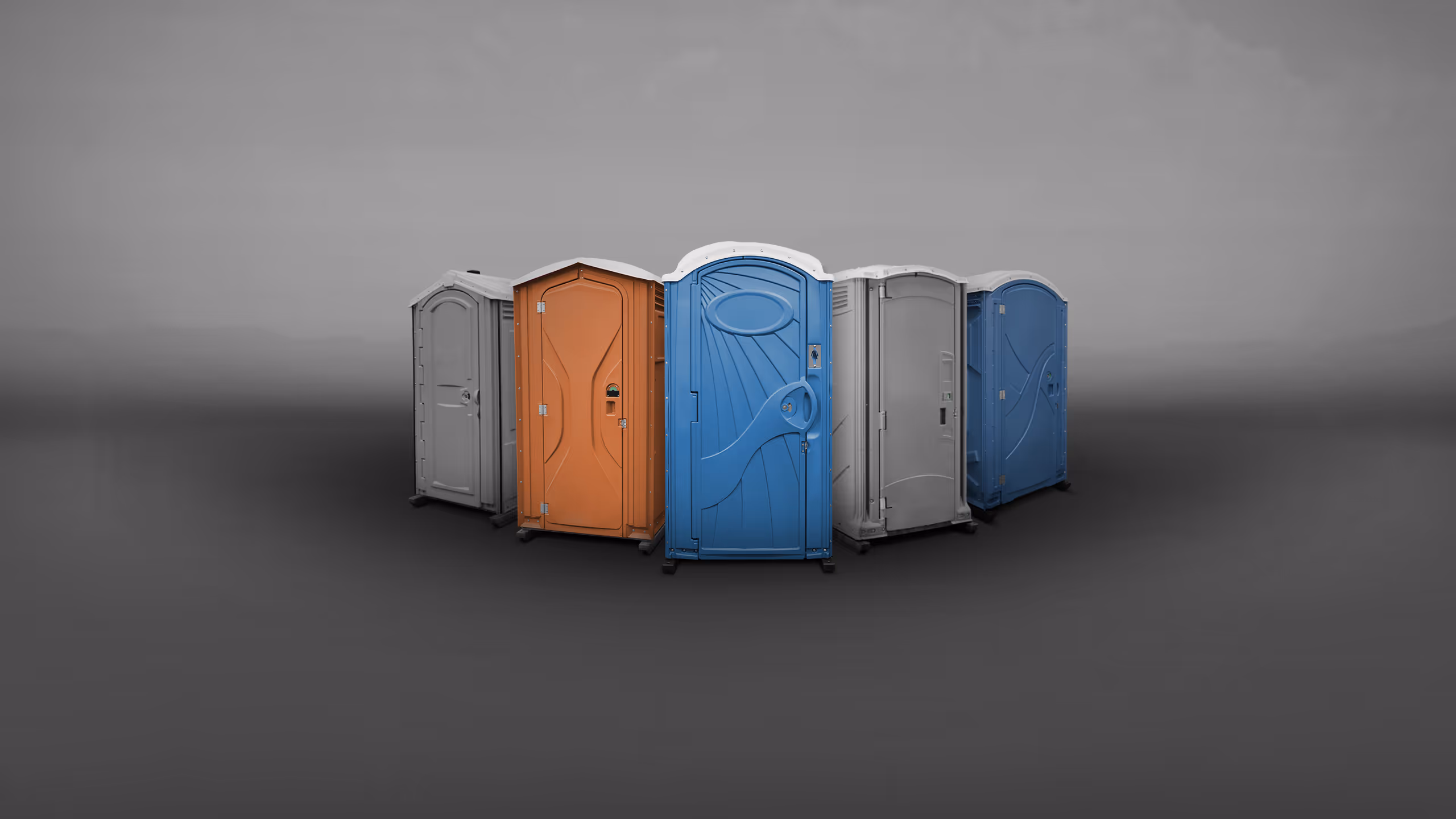 A group of portable toilets in various colors—orange, blue, gray—arranged in a semi-circle.