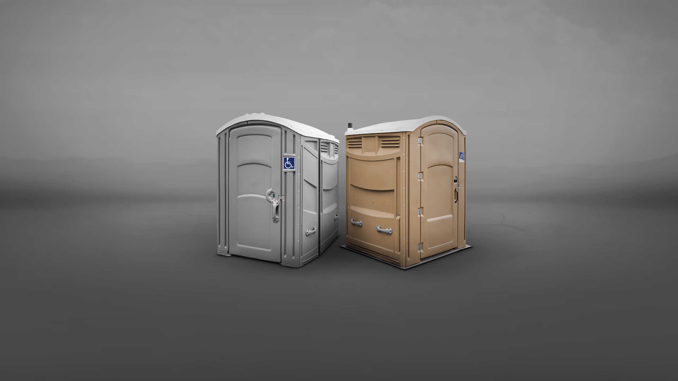 Two portable restrooms, one grey and one beige, positioned closely together against a gray