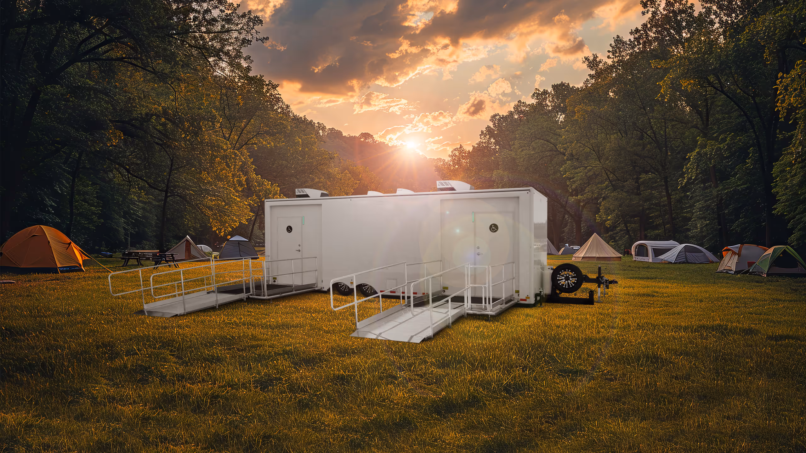 ADA Laundry Trailer with six stations, set in a campsite with tents under a sunset sky.